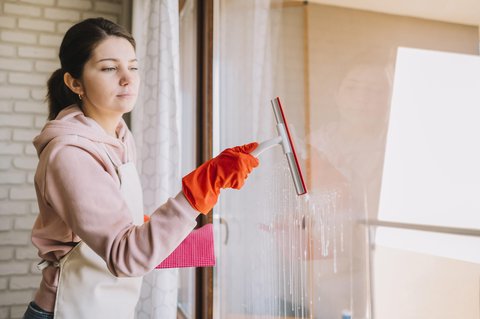mujer limpiando los cristales con un limpiacristales