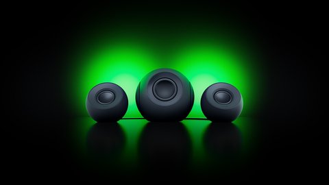 Los dos satélites y el subwoofer del Razer Mako, con iluminación verde proyectada sobre la pared
