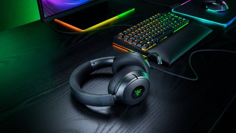 Los auriculares Razer Kraken V4 X apoyados en un escritorio junto a un teclado y un ratón con iluminación RGB