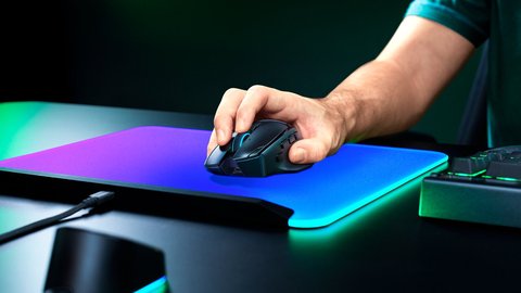 Mano sujetando el Razer Basilisk V4 Pro sobre una alfombrilla iluminada