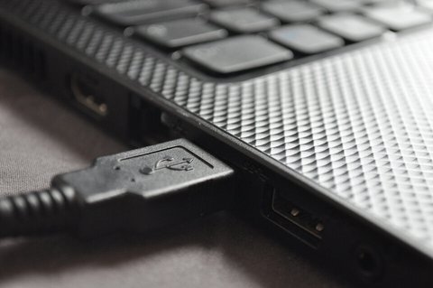 Puerto USB de un portátil con las siglas SS serigrafiadas al lado y el logo del tridente USB en el conector