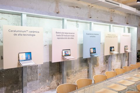 Paneles con las características del Zenbook 14 y portátiles expuestos en una sala con paredes de piedra