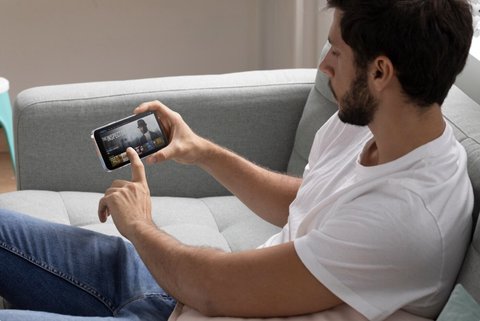 Persona jugando con el móvil tumbada en un sofá